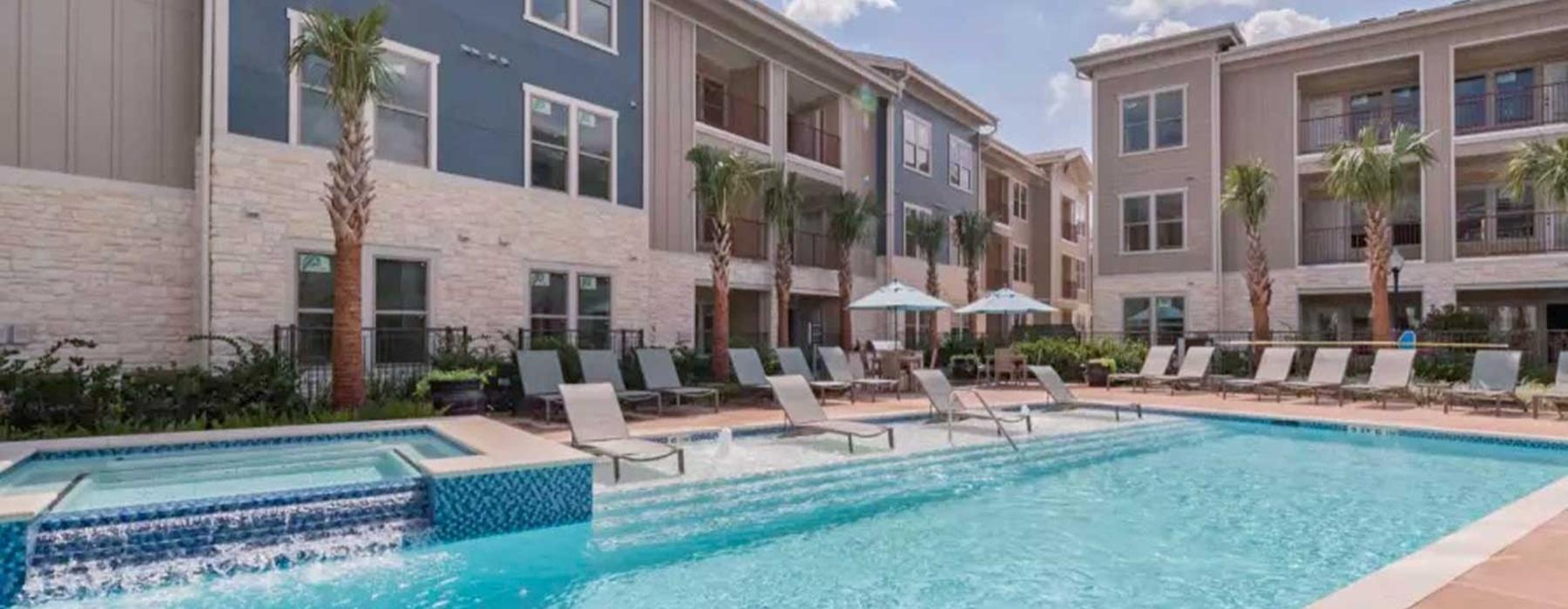 a pool with chairs and umbrellas by a building